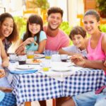 bigstock-Two-Families-Eating-Meal-At-Ou-78000803-e1765984015250