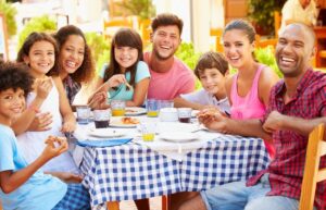 bigstock-Two-Families-Eating-Meal-At-Ou-78000803-e1765984015250